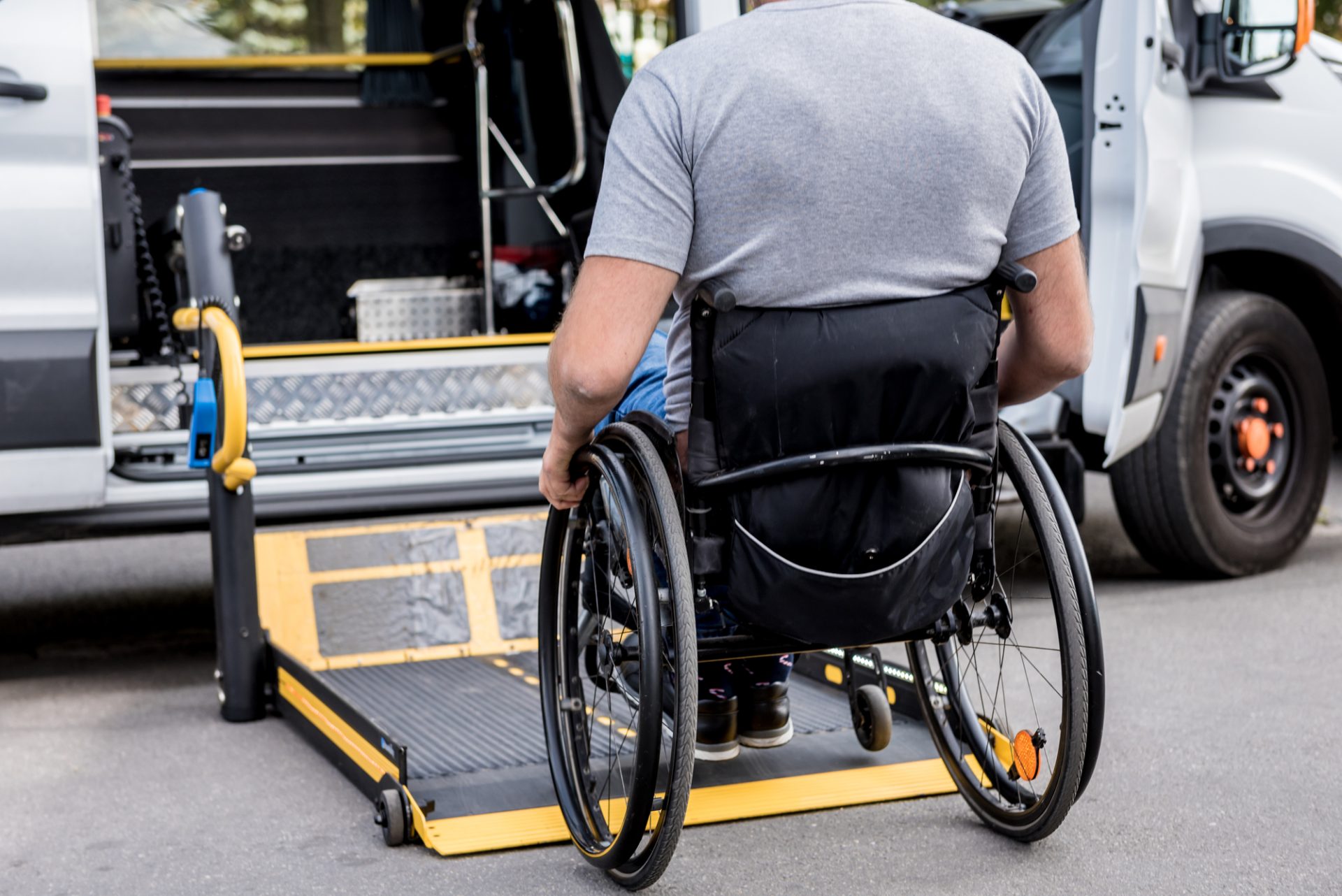 A man in a wheelchair on a lift of a vehicle